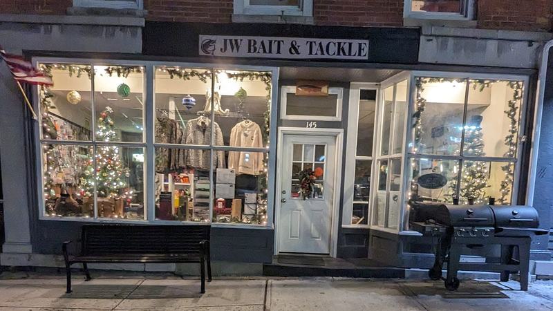 The shop at night in December, windows lit and garlanded, a bench out front and a smoker parked by the door